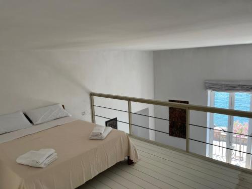 a white bedroom with a bed and a balcony at MARE DI NAPOLI in Pozzuoli