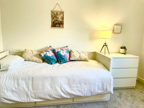 1 dormitorio con cama blanca con almohadas y vestidor en Modern chic summer holiday retreat. en Newquay