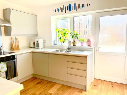 a kitchen with white cabinets and a sink at Modern chic summer holiday retreat. in Newquay