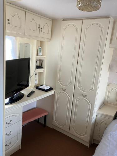 a bedroom with white cabinets and a desk with a television at Caravan 13 Stonehaven recreation grounds in Stonehaven