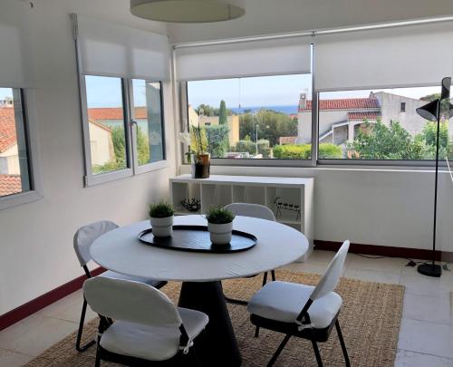 un salon avec une table, des chaises et des fenêtres dans l'établissement La Suite 68 Bandol avec jardin et parking privatif, à Bandol