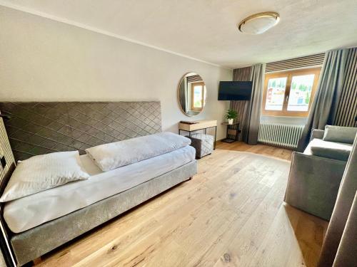 a bedroom with a bed and a chair and a mirror at Haus Schrofenstein in Lech am Arlberg