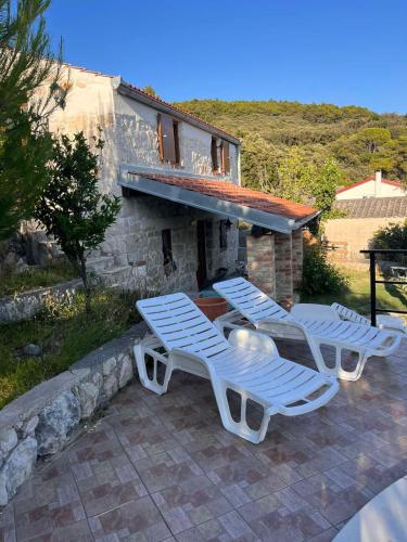a group of lounge chairs sitting next to a house at konoba in Rab