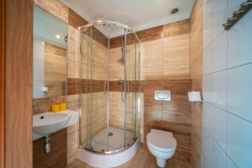 a bathroom with a shower and a toilet and a sink at Hotel Górski Kalatówki in Zakopane