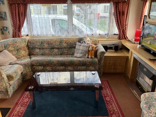 a living room with a couch with a teddy bear sitting on it at Caravan 13 Stonehaven recreation grounds in Stonehaven