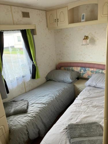 two beds in a small room with a window at Caravan 13 Stonehaven recreation grounds in Stonehaven