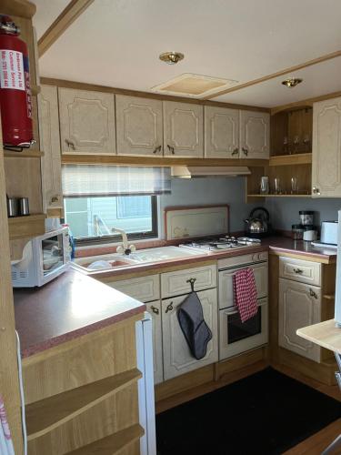 a kitchen with white cabinets and a stove top oven at Caravan 13 Stonehaven recreation grounds in Stonehaven