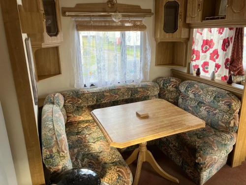 a living room with a couch and a wooden table at Caravan 13 Stonehaven recreation grounds in Stonehaven