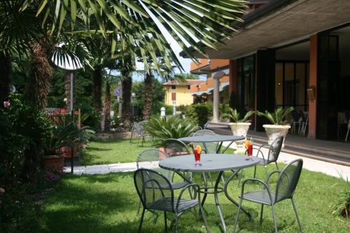 two tables and chairs with toy figurines on the grass at Residence Miralago Rooms & Apartments in Manerba del Garda