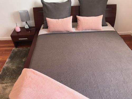 - un grand lit avec des oreillers roses et gris dans l'établissement Nice Stay - La Noue, à Villeneuve-la-Garenne