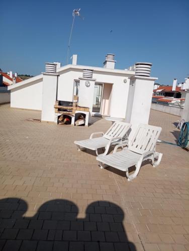 two white lounge chairs sitting on a brick patio at Apartamento Costa Azul in Costa da Caparica