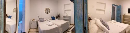 a white room with two beds and a mirror at Casarão Jeri in Jericoacoara