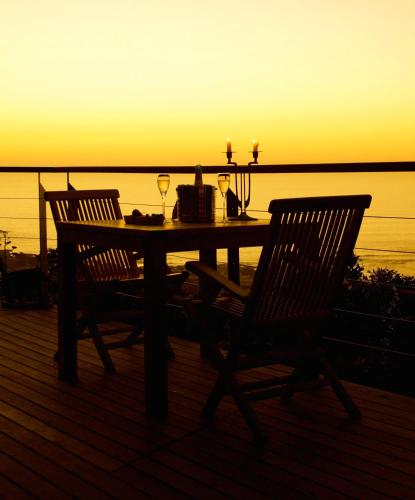 a table with two chairs on a deck with a sunset at Boutique@10 in Cape Town