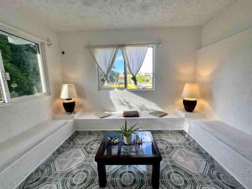 a white room with a table and two windows at Apartment located two blocks from the sea in Cozumel