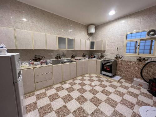 a kitchen with white cabinets and a checkered floor at القرى in Abha