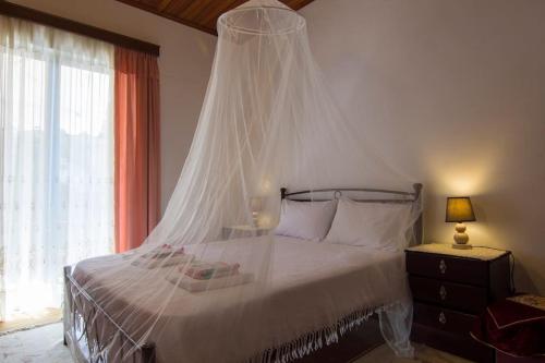 a bedroom with a bed with a mosquito net at Nikos apartment - Lakka Paxos in Lákka