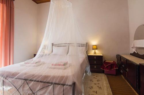 a bedroom with a white bed with a mosquito net at Nikos apartment - Lakka Paxos in Lákka
