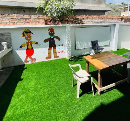 a yard with a table and a wall with a mural at Apartamento lujoso frente al mar in Crucita