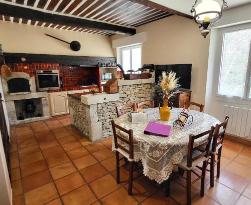 ein Esszimmer mit Tisch und Stühlen und eine Küche in der Unterkunft "La Massette du Cheval Blanc" Villa de caractère en pierre in LʼIsle-sur-la-Sorgue