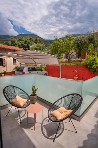 two chairs and a table on a balcony at Rousis Studios in Parga
