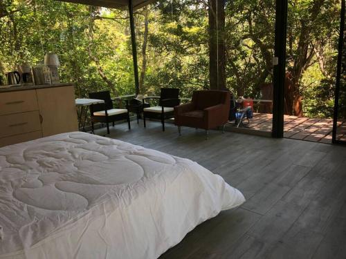 a bedroom with a white bed and a living room at Cabaña de montaña espectacular in Liberia