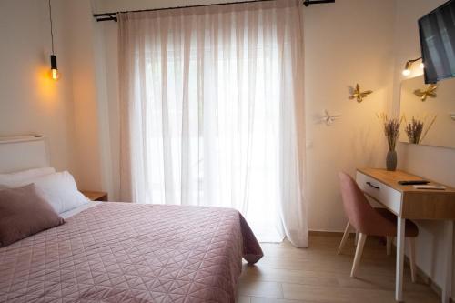 a bedroom with a bed and a desk and a window at Rousis Studios in Parga