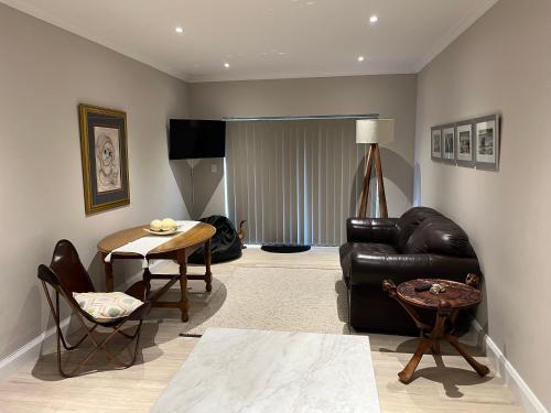 a living room with a black leather couch and a table at Metanoia Kingswood Golf Estate in George