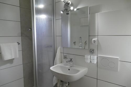 biała łazienka z umywalką i prysznicem w obiekcie Ferienwohnung am Holdereggenpark w mieście Lindau