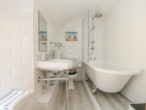 Baño blanco con bañera y lavamanos en The Hideaway, en Scarborough