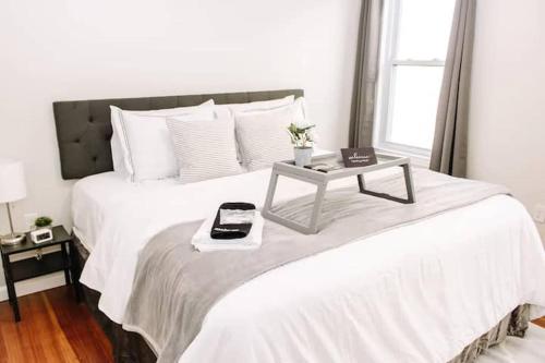 Una cama blanca con una mesa encima. en 5BR triple decker apartment – 15 mins to City en Boston