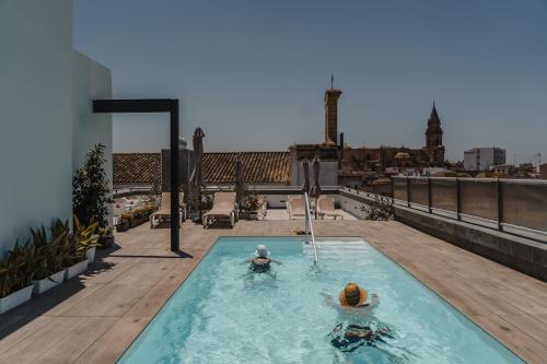 2 persone in una piscina in cima a un edificio di esZentrico Suites Jerez a Jerez de la Frontera