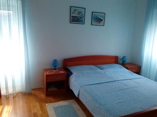 ein Schlafzimmer mit einem Bett und einem Nachttisch mit zwei Lampen in der Unterkunft Apartment Pavešić 1 in Mali Lošinj