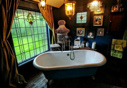 Cedar Oaks Inn The Birdcage Saloon في ديكنسون: حوض استحمام في الحمام مع نوافذ زجاجية ملطخة