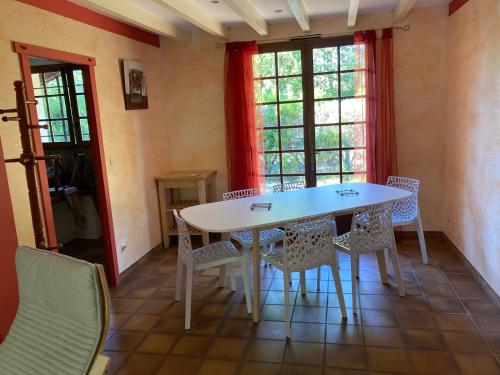une table et des chaises blanches dans une chambre avec fenêtres dans l'établissement maison moliets, à Moliets-et-Maa