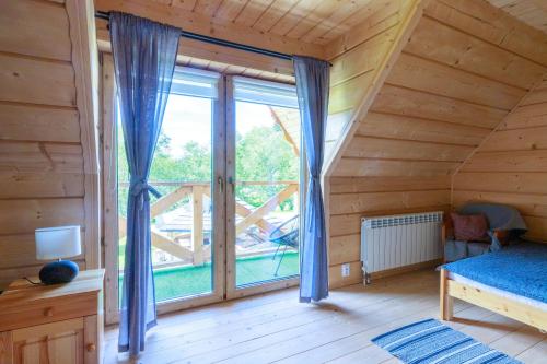 ein Schlafzimmer mit einem großen Fenster in einem Holzhaus in der Unterkunft Domki Burego w Białce Tatrzańskiej in Białka Tatrzańska