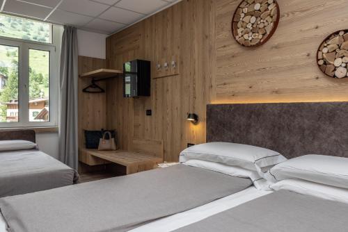 a bedroom with two beds and a tv on the wall at Hotel Pejo in Peio Fonti