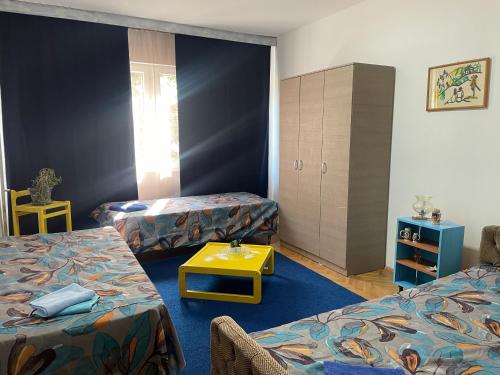 een kamer met 2 bedden en een gele tafel bij Central City Touch in Skopje
