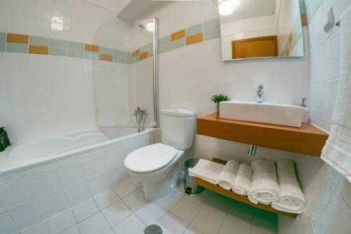 Baño blanco con aseo y lavamanos en Kora Home, en Santa Cruz