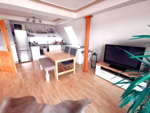 a living room with a table and a television and a kitchen at Stilvolle hochwertige Wohnung im Stadtzentrum in Jena
