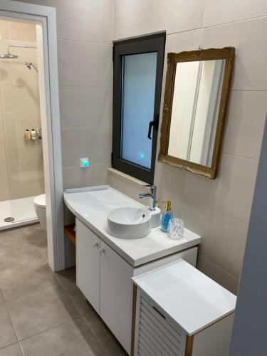 a white bathroom with a sink and a mirror at Patriko-Cozy villa on the foot of the mountains in Ammoudari