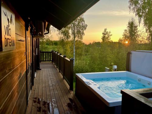 a hot tub on a deck with the sunset in the background at Villa Breikki Himos - Alpha & Bravo Incl WiFi, Sauna, Jacuzzi for extra fee in Jämsä