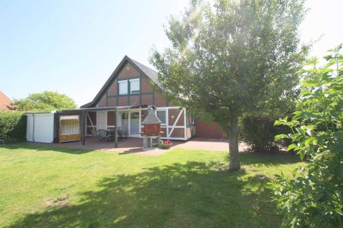 a house with a tree in the yard at FH Norderpiep 22 Sauna u Kamin in Friedrichskoog-Spitze