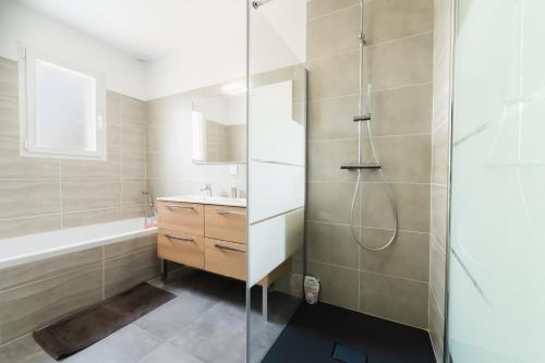 een badkamer met een douche, een wastafel en een bad bij * * La maison du bonheur * * Piscine chauffée in Fargues-Saint-Hilaire