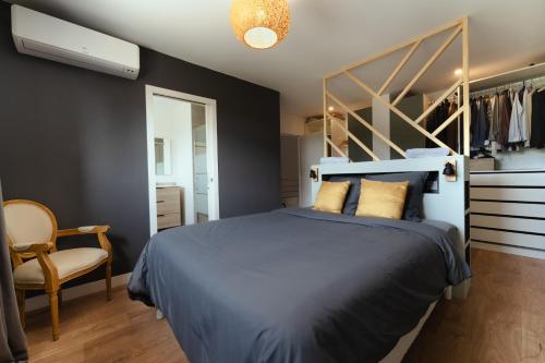 een slaapkamer met een blauw bed en een stoel bij * * La maison du bonheur * * Piscine chauffée in Fargues-Saint-Hilaire