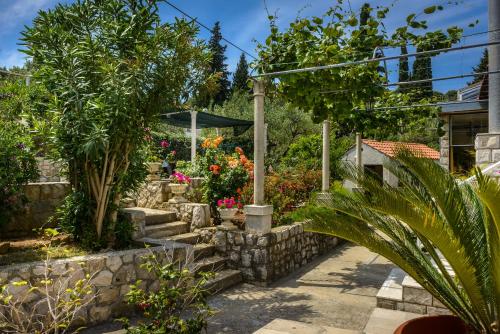 a garden with flowers and a stone wall at Villa Mali Raj in Zaton
