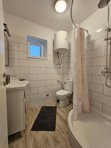 a bathroom with a toilet and a sink and a tub at Apartman Lila in Čunski