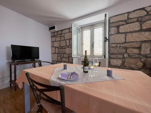 a dining room with a table with a bottle of wine at Apartman Aterina in Korčula