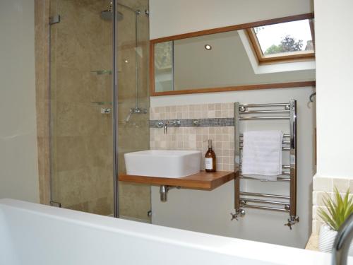 a bathroom with a sink and a shower with a mirror at Goyt Cottage in Stockport