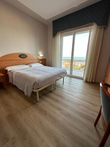 a bedroom with a large bed and a large window at Hotel Costa Verde in Pineto