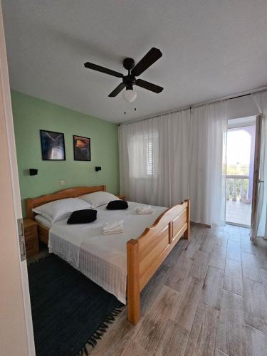 a bedroom with a large bed with a ceiling fan at Apartman Lila in Čunski
